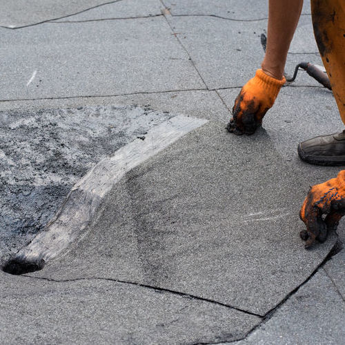 A Roofer Repairs a Damaged Commercial Roof